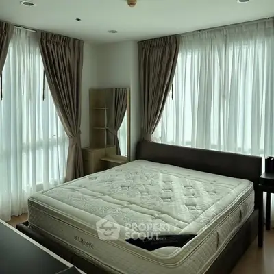 Spacious bedroom with large windows and elegant curtains, featuring a comfortable bed and stylish decor.