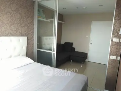 Modern bedroom with elegant wallpaper and cozy seating area in a stylish apartment.