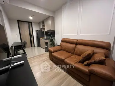 Modern living room with leather sofa and open kitchen layout in stylish apartment.