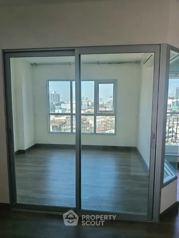 Modern apartment with glass sliding doors and city view, featuring sleek flooring and abundant natural light.