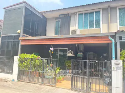 Charming two-story townhouse with gated entrance and lush greenery, perfect for modern family living.