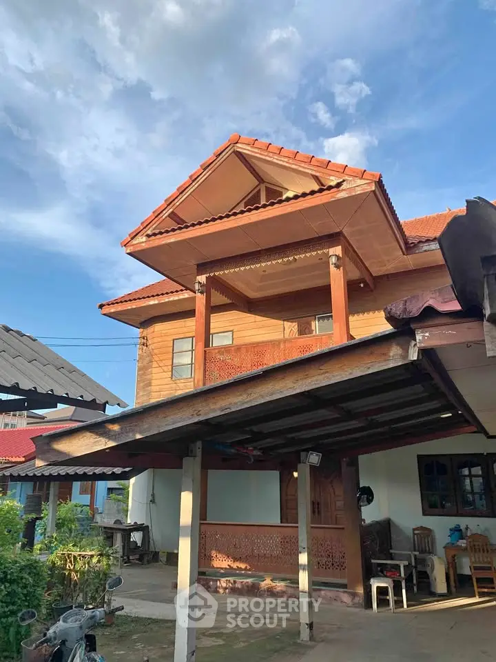 Charming two-story wooden house with traditional design and spacious balcony under a clear blue sky.