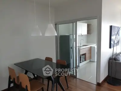 Modern dining area with glass table and view into sleek kitchen
