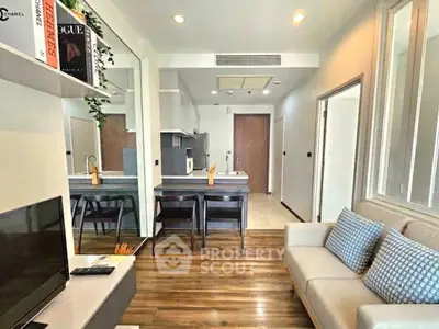 Modern living room with open kitchen, stylish decor, and wooden flooring in a cozy apartment.