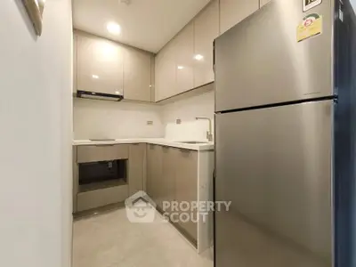 Modern kitchen with sleek cabinetry and stainless steel fridge in compact layout.
