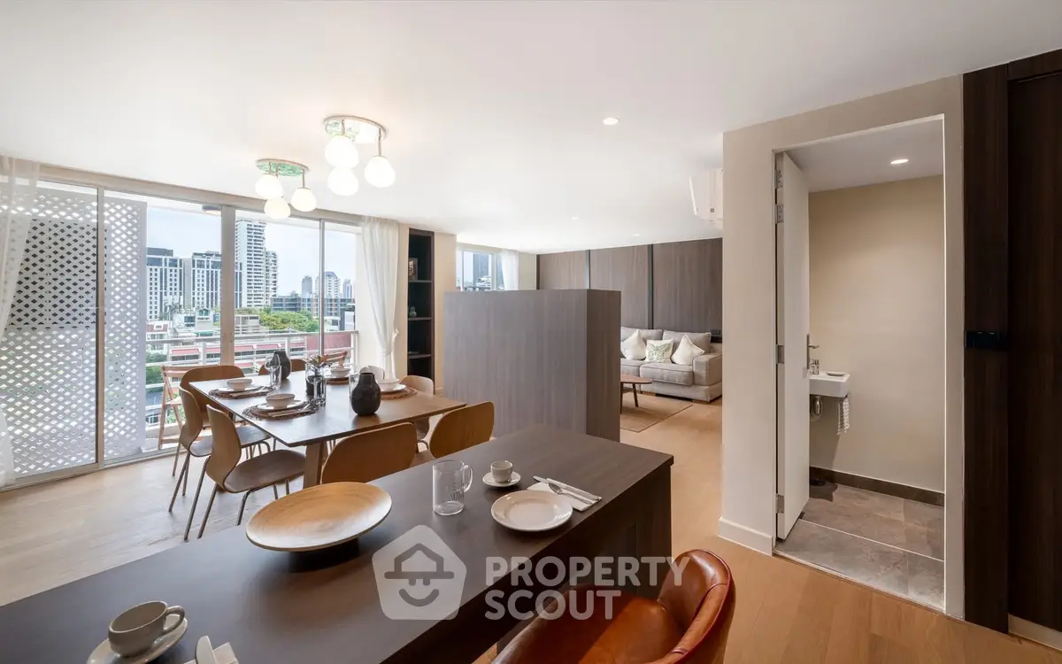 Spacious modern living room with dining area and city view, featuring elegant decor and natural light.