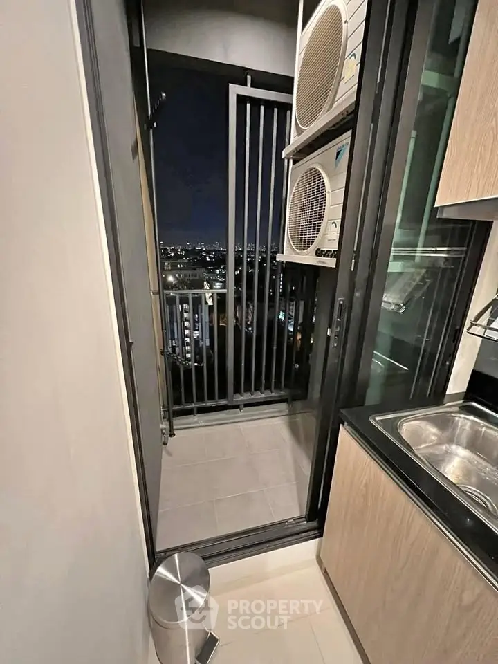 Modern apartment balcony with city view and kitchen access at night
