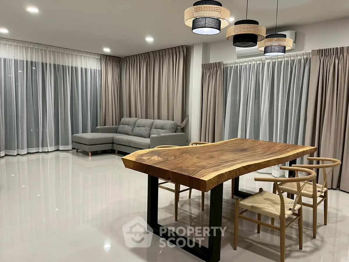Spacious modern living room with elegant wooden dining table and cozy gray sofa.