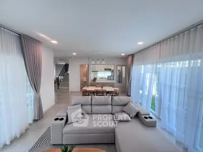 Spacious modern living room with elegant decor and open layout leading to dining area and kitchen.