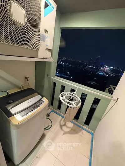 High-rise balcony with city view, featuring washing machine and air conditioning unit.