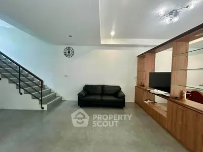 Spacious modern living room with sleek staircase and stylish shelving unit.