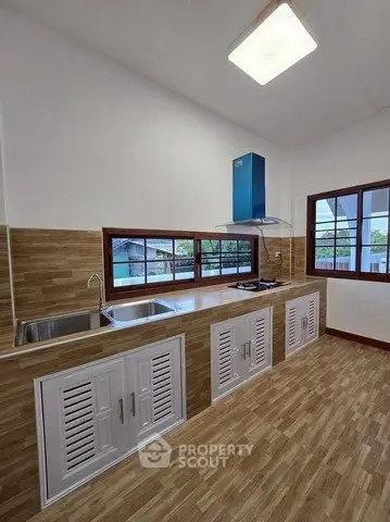 Modern kitchen with sleek design, featuring wooden flooring, large windows, and a gas stove for culinary enthusiasts.