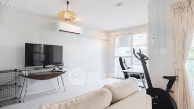 Bright modern living room with TV and exercise equipment, perfect for relaxation and fitness.