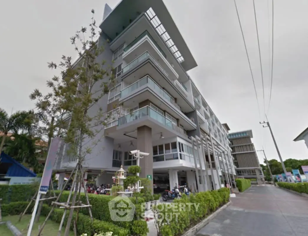 Modern multi-story apartment building with balconies and lush greenery