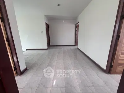 Spacious empty room with tiled flooring and wooden doors, perfect for customization.