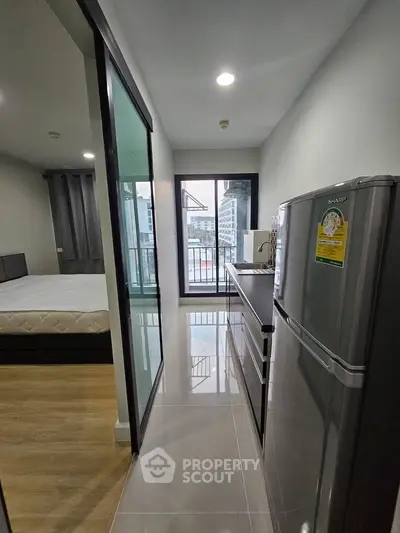 Modern apartment interior with sleek kitchen and cozy bedroom, featuring a balcony view.