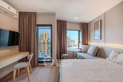 Modern bedroom with city view, featuring cozy seating and sleek decor.