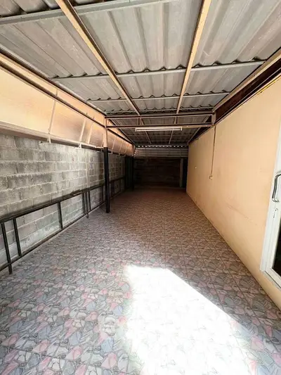 Spacious covered outdoor area with tiled flooring and metal roof, perfect for versatile use.