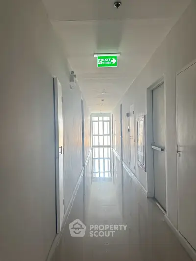 Bright corridor with polished floors and exit sign in modern building