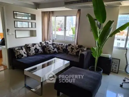 Modern living room with stylish sectional sofa and large windows offering city views.