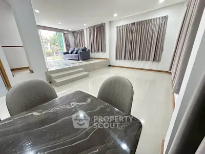 Spacious modern living room with elegant marble dining table and large windows for natural light.