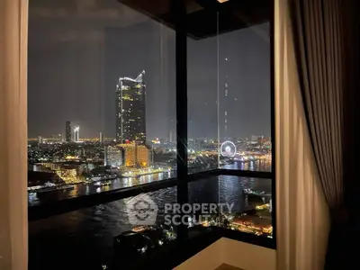 Stunning cityscape view from a high-rise apartment window at night, overlooking a river and illuminated skyline.