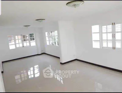 Spacious and bright empty living room with large windows and tiled floor.
