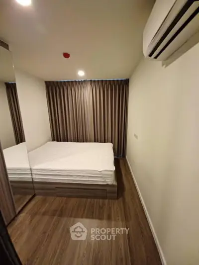 Cozy bedroom with wooden flooring and air conditioning in modern apartment.