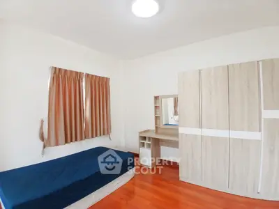 Spacious bedroom with wooden flooring and modern furniture