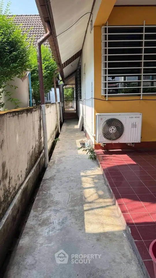 Charming exterior walkway with air conditioning unit and tiled patio area.