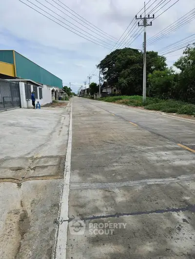 Quiet suburban street with industrial buildings and lush greenery, ideal for commercial real estate opportunities.
