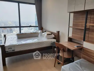 Modern bedroom with city view, wooden furniture, and large window in high-rise apartment.