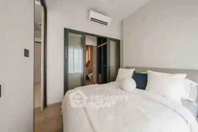 Cozy bedroom with modern decor and air conditioning, featuring sliding doors leading to an ensuite bathroom.