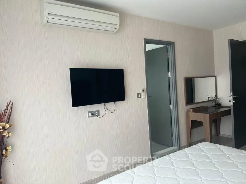Modern bedroom with wall-mounted TV and air conditioning unit, featuring a minimalist design.
