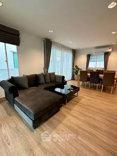 Spacious living room with modern furniture and dining area, featuring large windows and elegant decor.