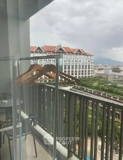 Spacious balcony with scenic view of modern building and lush greenery, perfect for relaxation.
