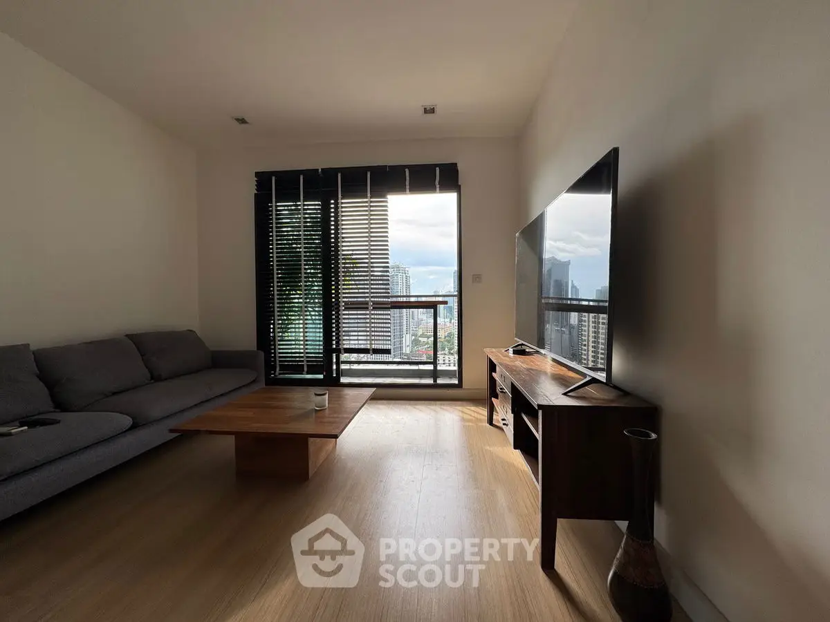 Modern living room with city view, featuring sleek furniture and large windows for natural light.