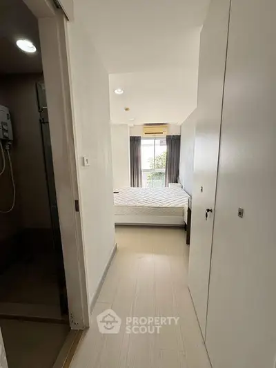 Modern bedroom with natural light and minimalist design, featuring a comfortable bed and air conditioning.
