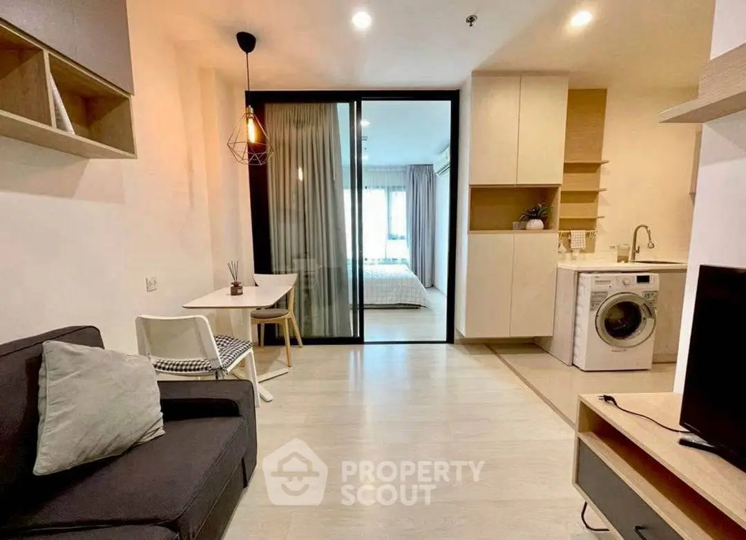 Modern studio apartment with open layout, featuring cozy living area and in-unit washing machine.