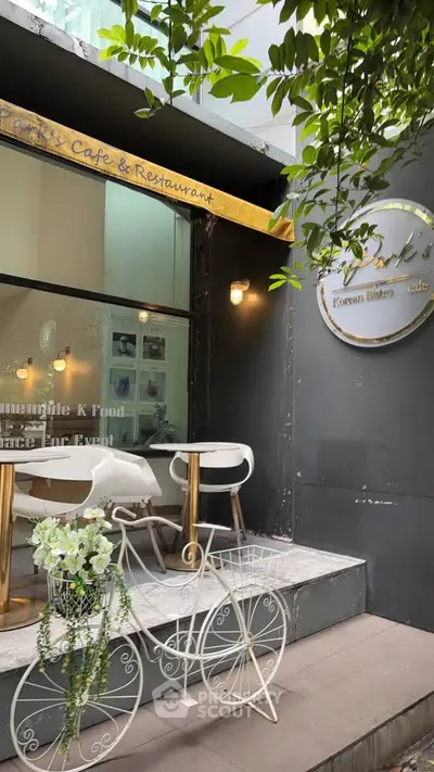 Charming cafe entrance with stylish outdoor seating and decorative bicycle planter.