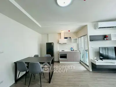 Modern open-plan living room with kitchen, dining area, and sleek furnishings in a bright apartment.