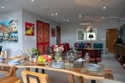 Spacious living room with modern decor and dining area, featuring vibrant artwork and elegant furnishings.