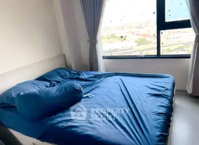 Cozy bedroom with large window offering city views and elegant blue bedding.