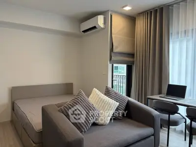 Modern studio apartment with cozy bed, stylish sofa, and work desk, perfect for urban living.