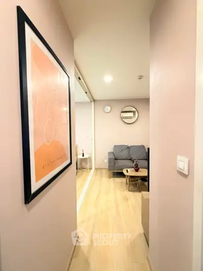 Stylish apartment hallway leading to cozy living room with modern decor and wooden flooring.