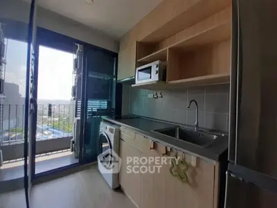 Modern kitchen with balcony view, featuring washing machine and microwave, perfect for urban living.