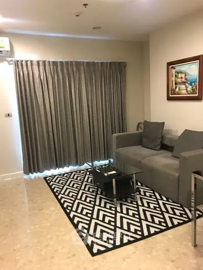 Cozy living room with modern gray sofa, stylish rug, and elegant curtains in a chic apartment.