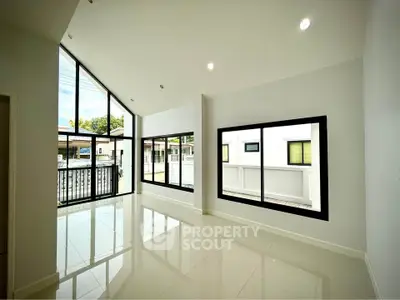 Spacious modern living room with large windows and high ceilings, offering abundant natural light and a sleek design.