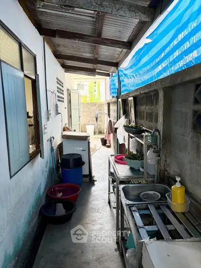 Functional outdoor kitchen area with sink and storage in a covered alleyway.