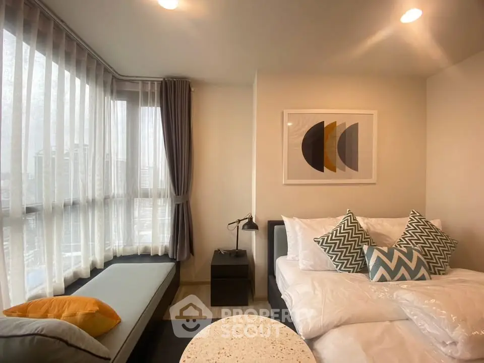 Modern bedroom with stylish decor and large windows offering natural light.